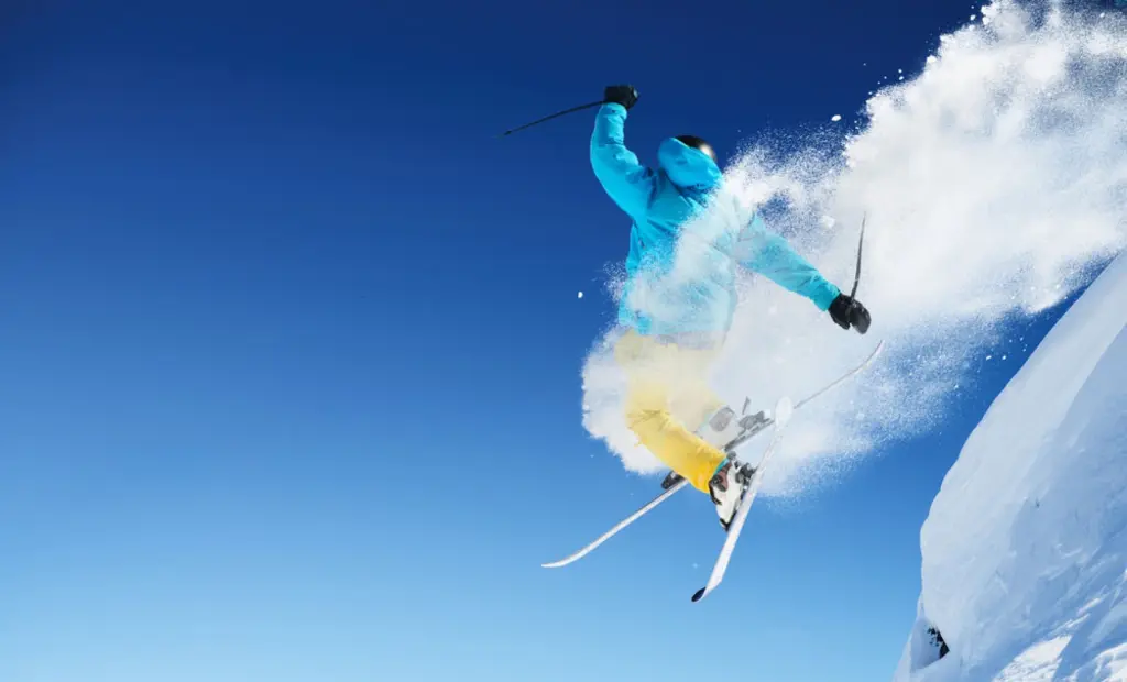 Un skieur en plein saut dans un nuage de poudreuse