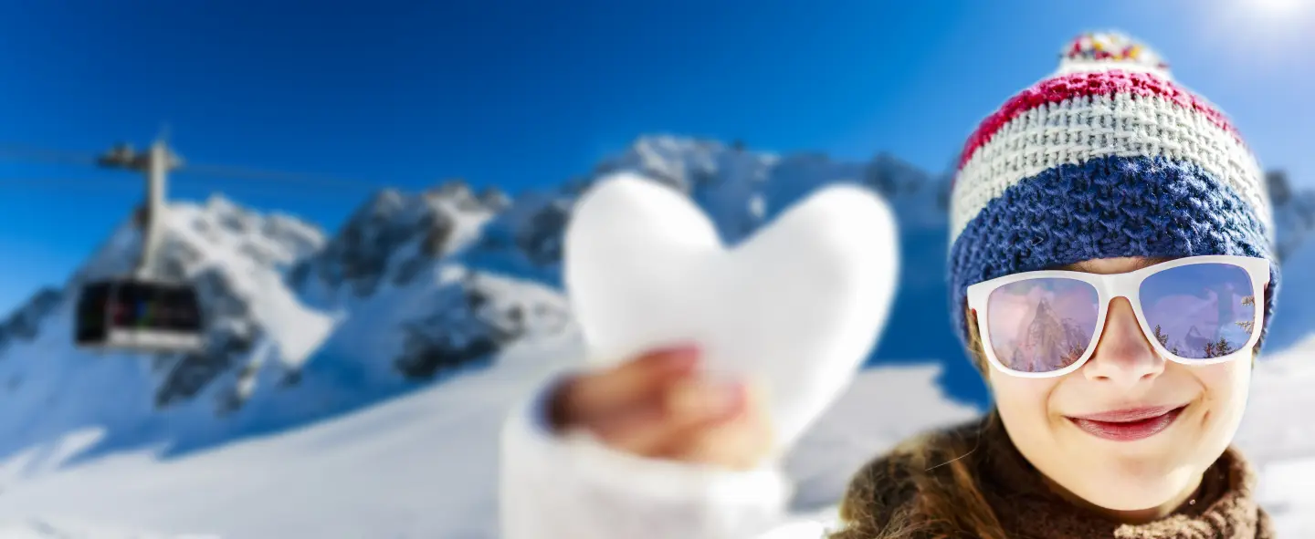 jeune fille en montagne tenant un coeur fait en neige