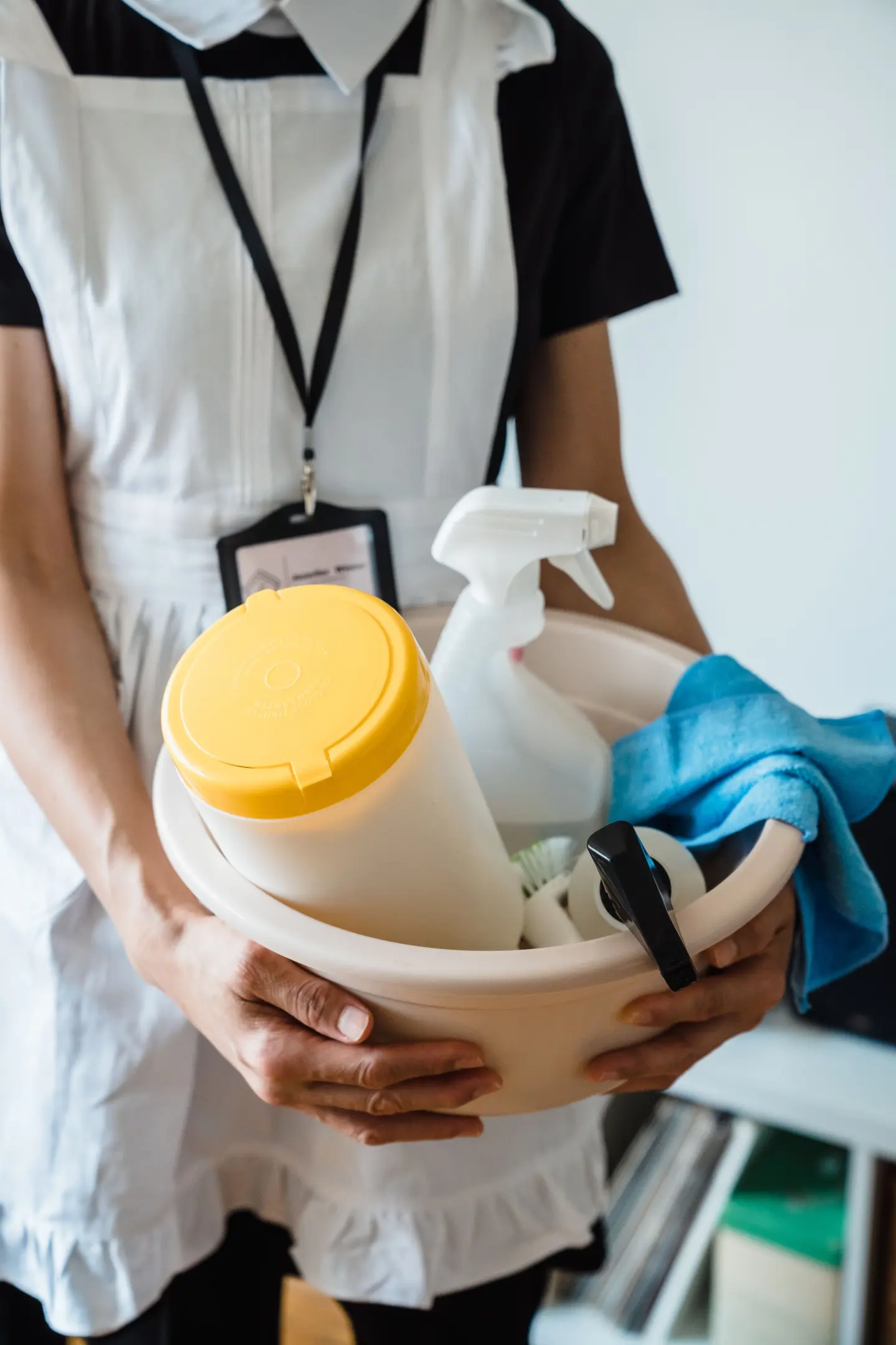 personne tenant une bassine rempli de matériel et produit pour faire le ménage