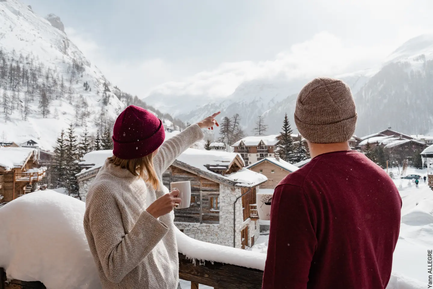 couple sur un balcon buvant un chocolat chaud et admirant le village de val d'isère en savoie