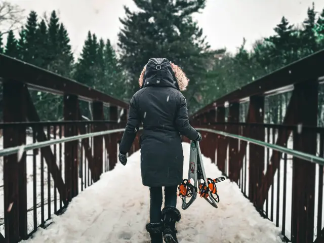 personne de dos tenant des raquettes dans la neige